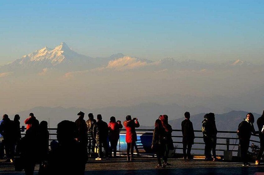 A group of people standing on a bridge overlooking a mountain range with snow-capped peaks. 2