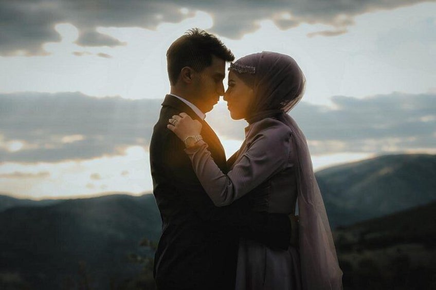 Un couple s’embrasse dans un paysage montagneux, avec un coucher de soleil en arrière-plan. 3