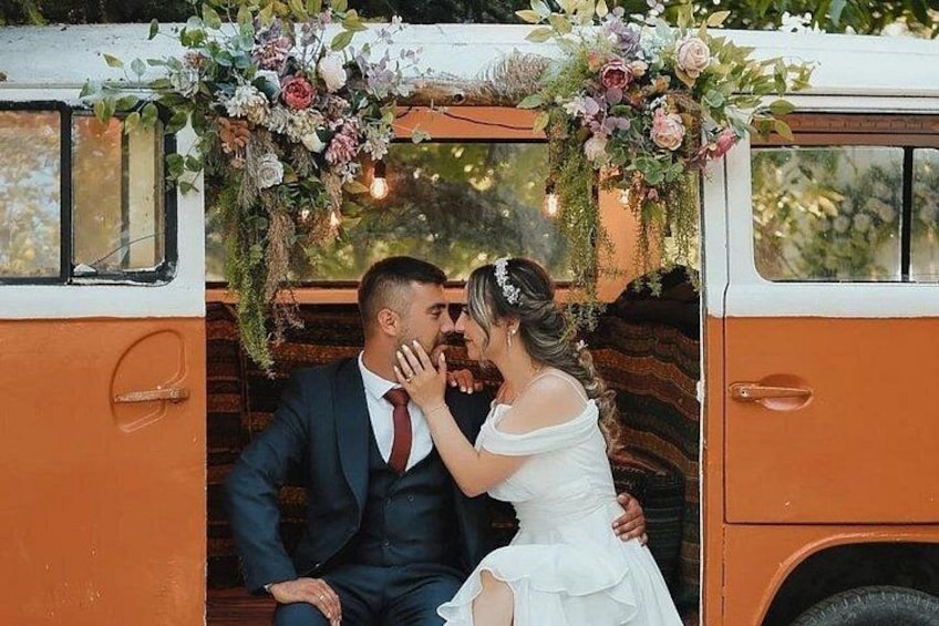 Un couple s’embrasse devant un véhicule d’époque décoré de motifs floraux. 1