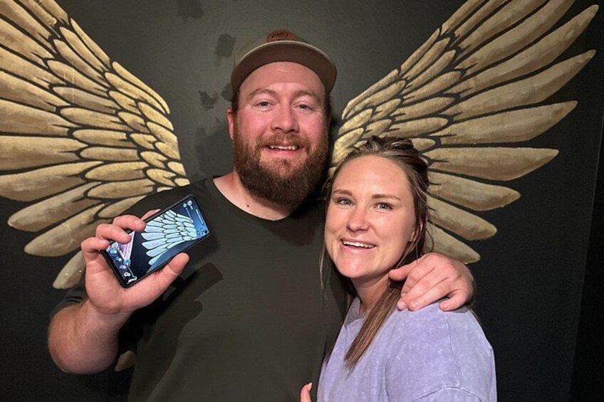 A person holding a smartphone with wings in the background. 3