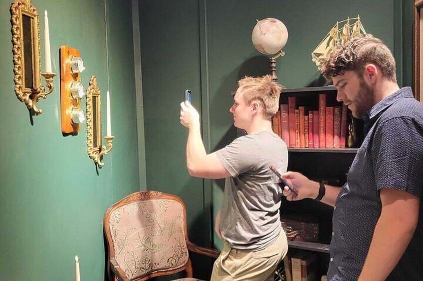 Twee personen maken een foto, een stoel, een boekenkast en wanddecoraties. 4