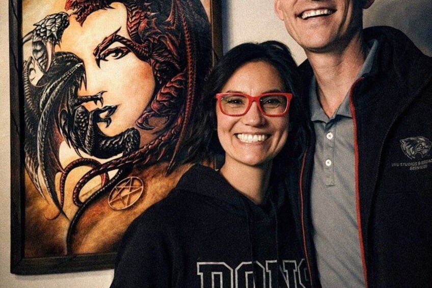 A person wearing a hoodie with a logo, a framed artwork with a snake and a pentagram, and a person in a jacket with a logo. 3