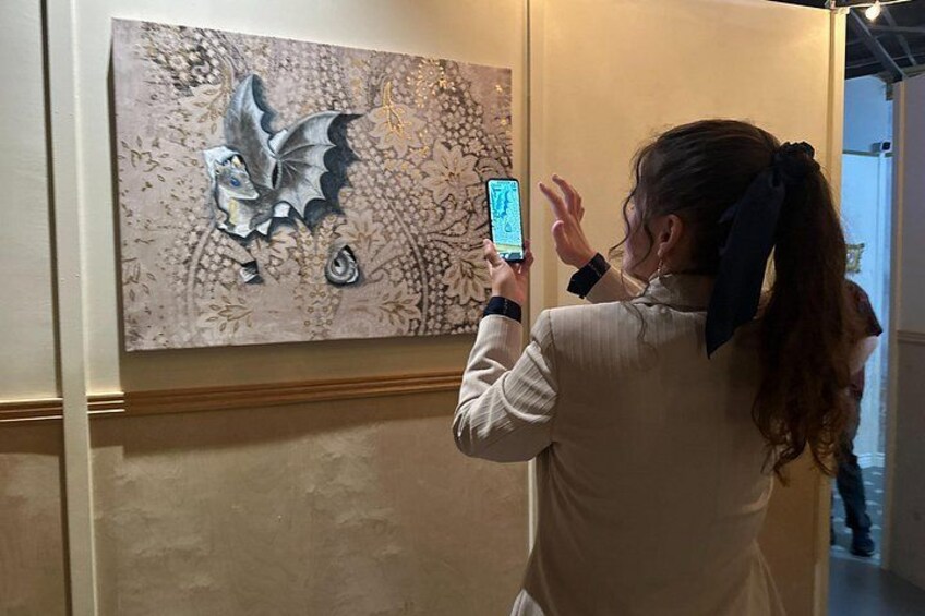 A person taking a photo of a painting with a dragonfly. 5