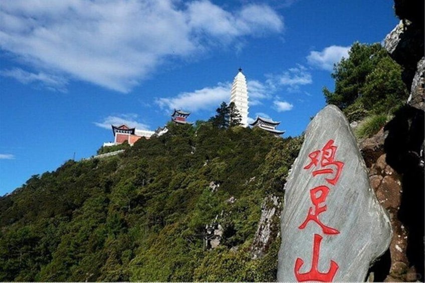 A mountainous landscape with traditional architecture, including pagodas and a large rock with Chinese characters. 1