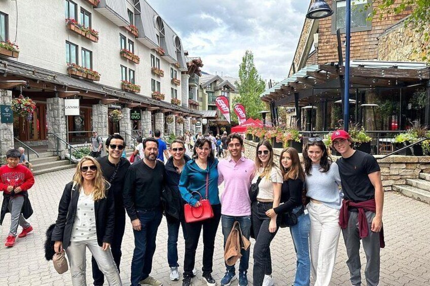 Un grupo de personas de pie en una plaza pública con edificios y una bandera al fondo. 4