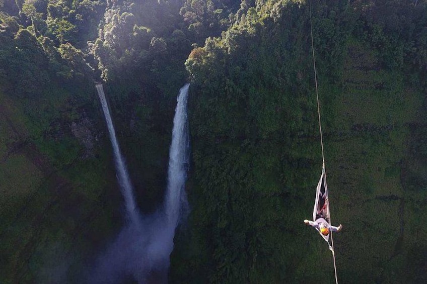 A person bungee jumping with two waterfalls in the background. 5