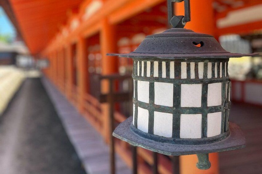 A traditional Japanese lantern with a grid pattern, hanging from a metal bracket. 3