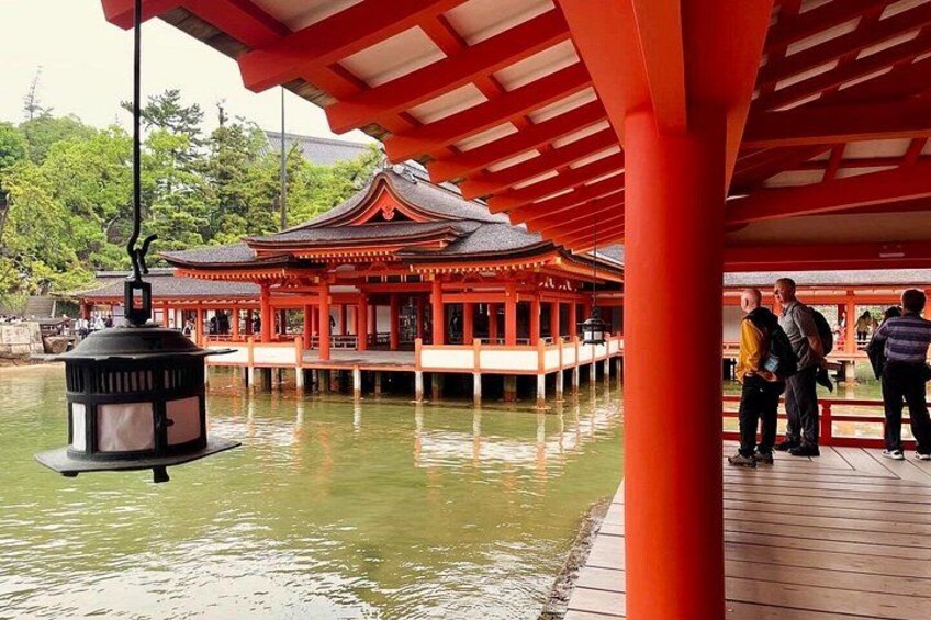 A traditional Japanese building with a red roof, a wooden walkway, and a hanging lantern. 1
