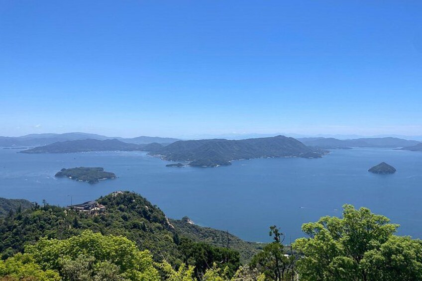 A coastal landscape with multiple islands, clear blue sky, and dense green foliage. 4