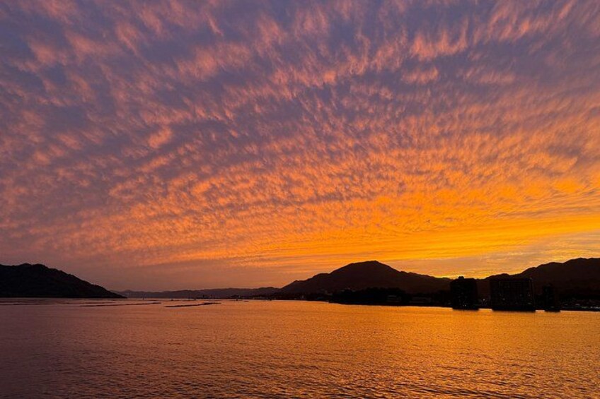 A sunset over a body of water with mountains in the background. 2
