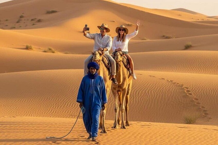 A desert landscape with sand dunes, a camel, and people riding the camel. 3