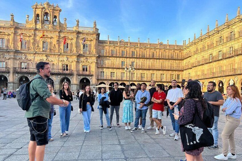 A group of people in a plaza with a large ornate building in the background. 2