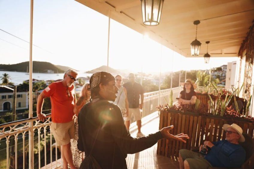 A group of people on a covered balcony overlooking a body of water. 3