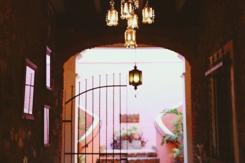 An arched doorway with a wrought iron gate, a hanging lantern, and a chandelier. 4