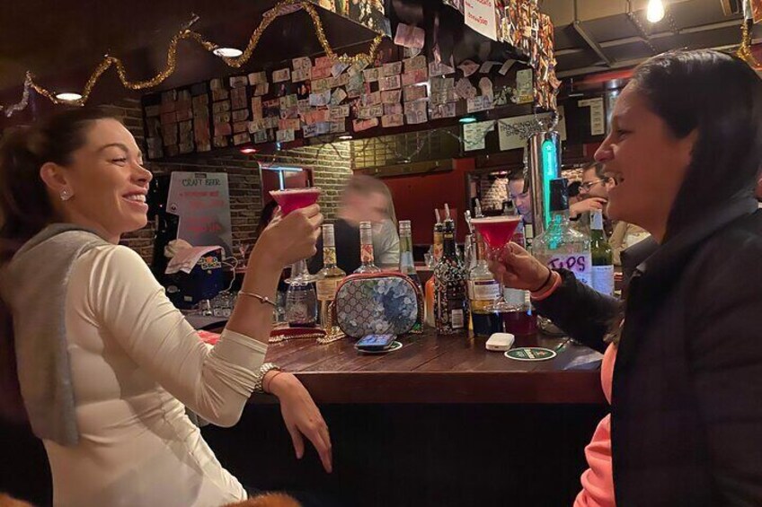 Two people toasting with martini glasses at a bar. 2