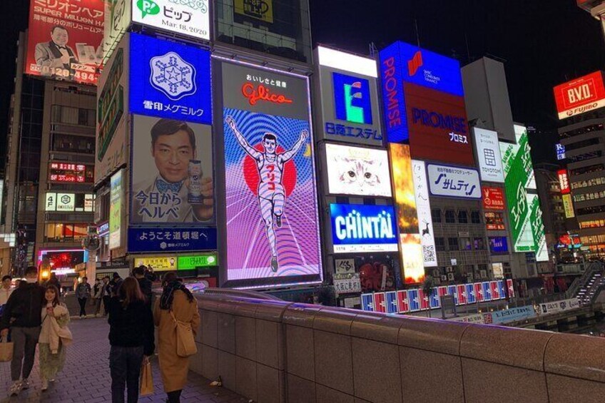 A busy urban street at night with illuminated billboards and advertisements. 3