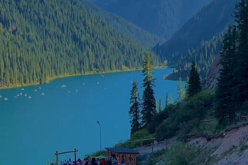 A lake surrounded by forested mountains, a small dock, and a gazebo. 1