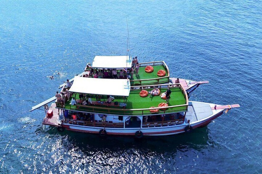 A boat with a green deck and multiple levels, floating on calm water. 3