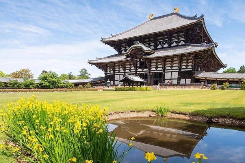 En traditionell japansk byggnad med en damm i förgrunden. 3