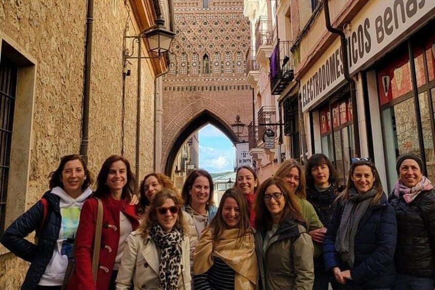 A group of people standing in a narrow street with a historic building in the background. 2