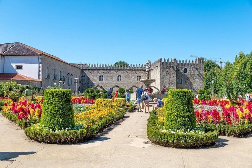 A historic building with a moat, surrounded by well-maintained flower beds and a clear sky. 3