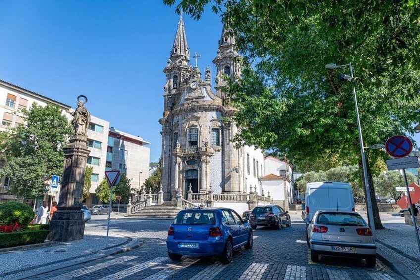 A street with cars, a statue, a church, and a traffic sign. 2