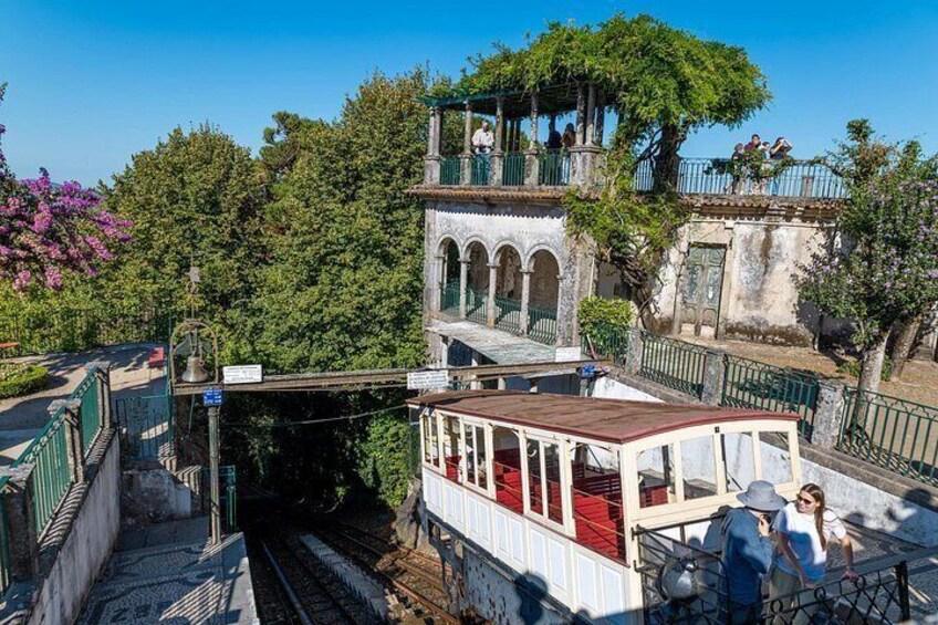 A train station with a covered waiting area, a pedestrian bridge, and a building with arched windows. 4