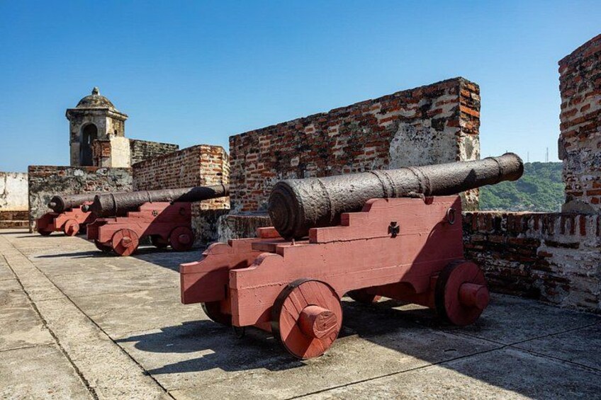 A row of red cannons on a concrete platform with brick walls in the background. 2