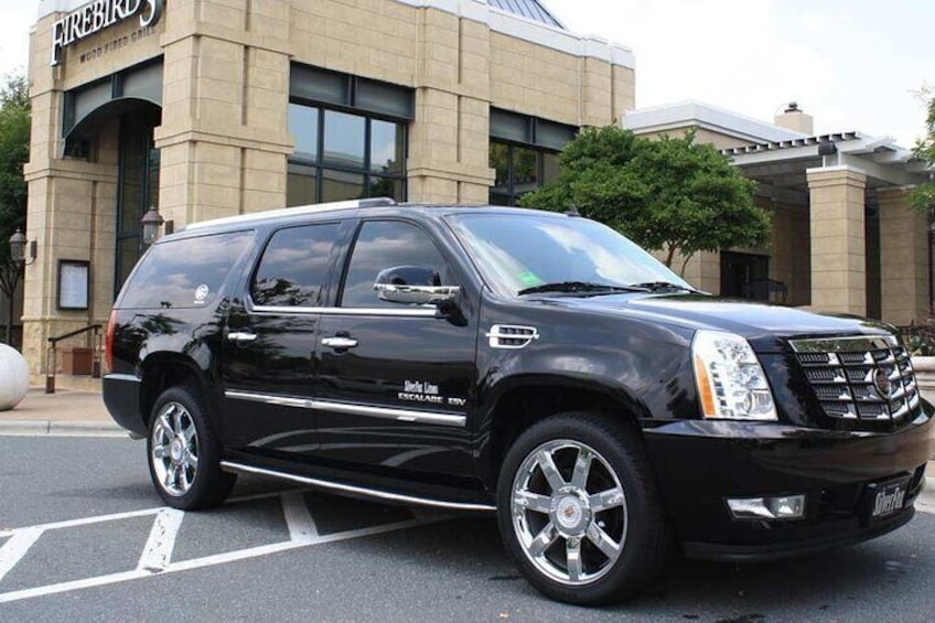 A black Cadillac Escalade SUV parked in front of a building with a sign that reads "Firebirds." 5