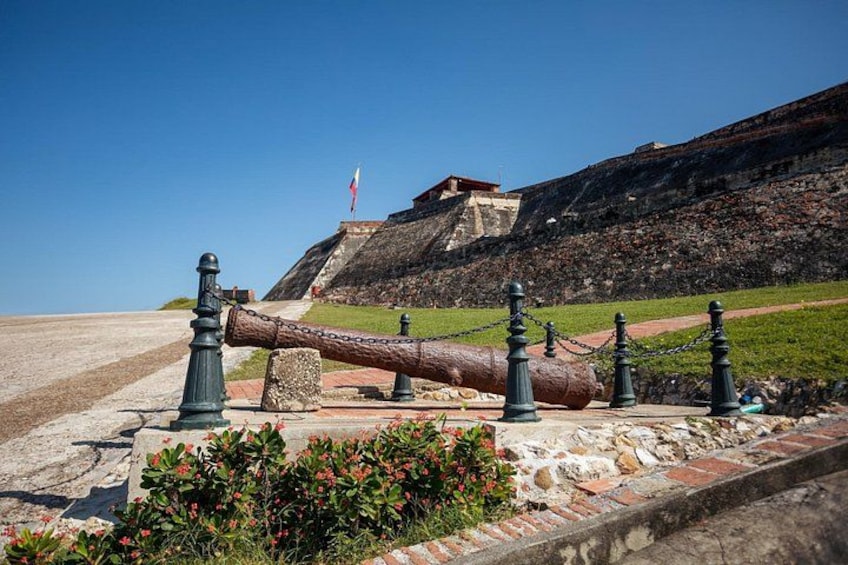 A cannon, a flag, and a building on a hill. 5