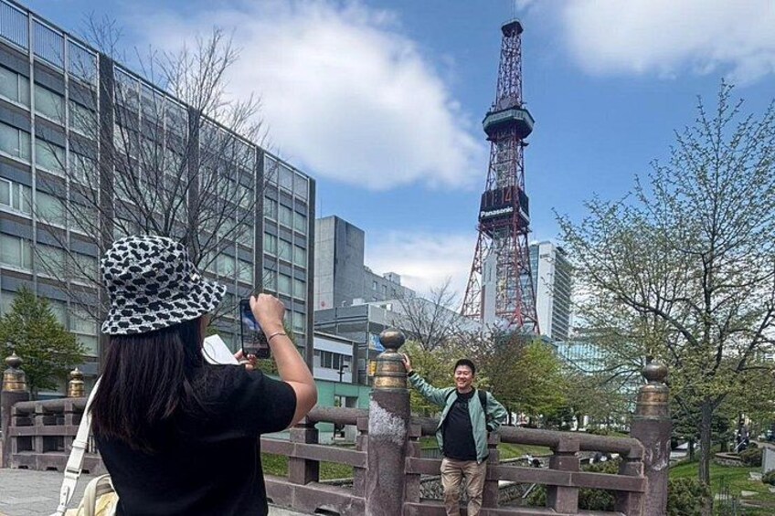 A person taking a photo with a camera, a bridge, and a tower in the background. 2