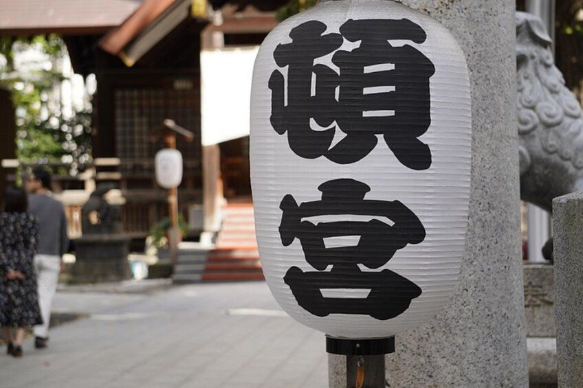A traditional Japanese lantern with black characters on a white background, mounted on a stone post. 3