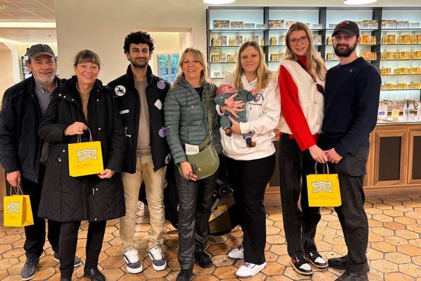 A group of people standing indoors, holding yellow shopping bags. 2