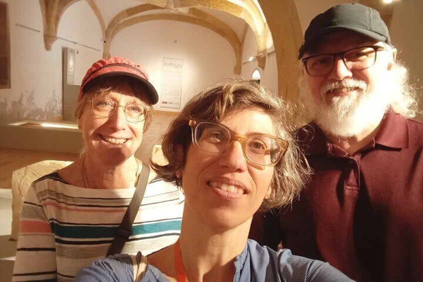 Three people in an indoor setting with arched ceilings and a display case. 2