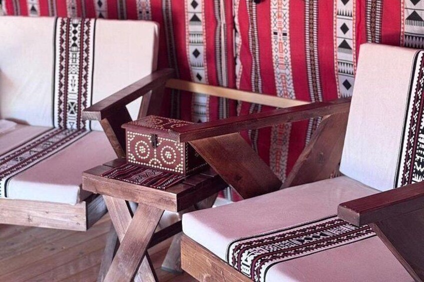 A wooden chair with a woven seat and backrest, a small wooden table with a woven box, and a patterned wall in the background. 4