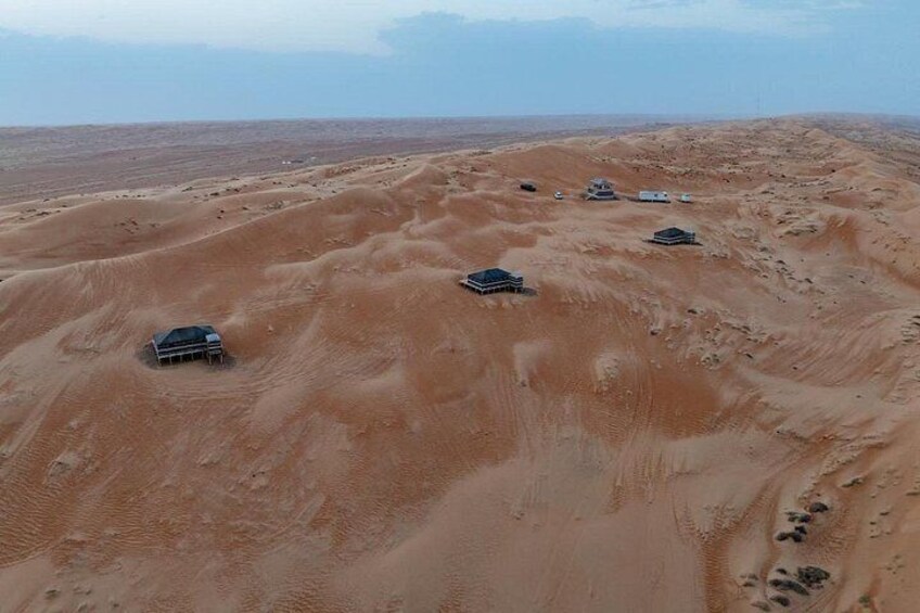 A desert landscape with four vehicles and a building. 5