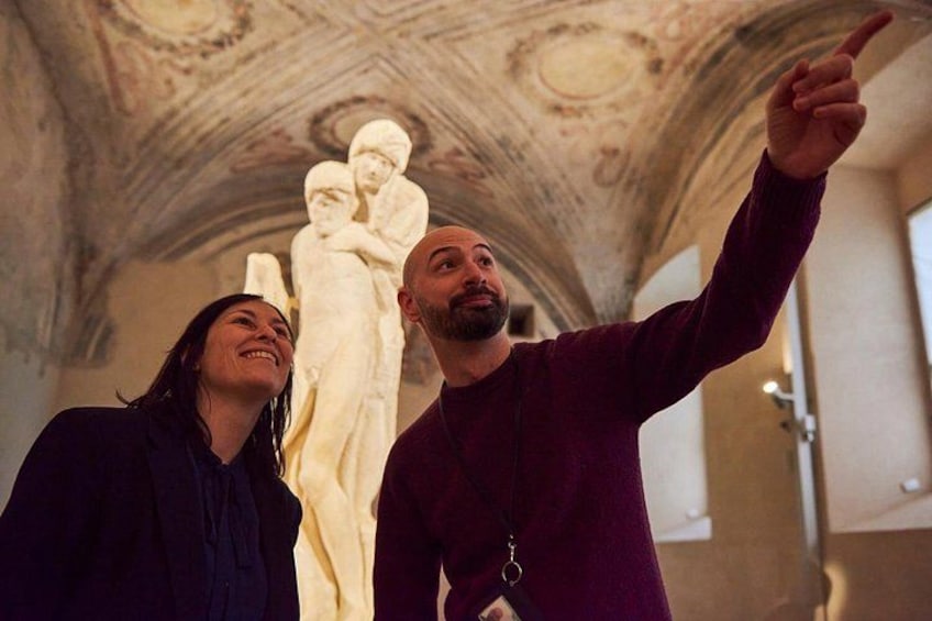 A person pointing at a sculpture in a building with a detailed ceiling. 5