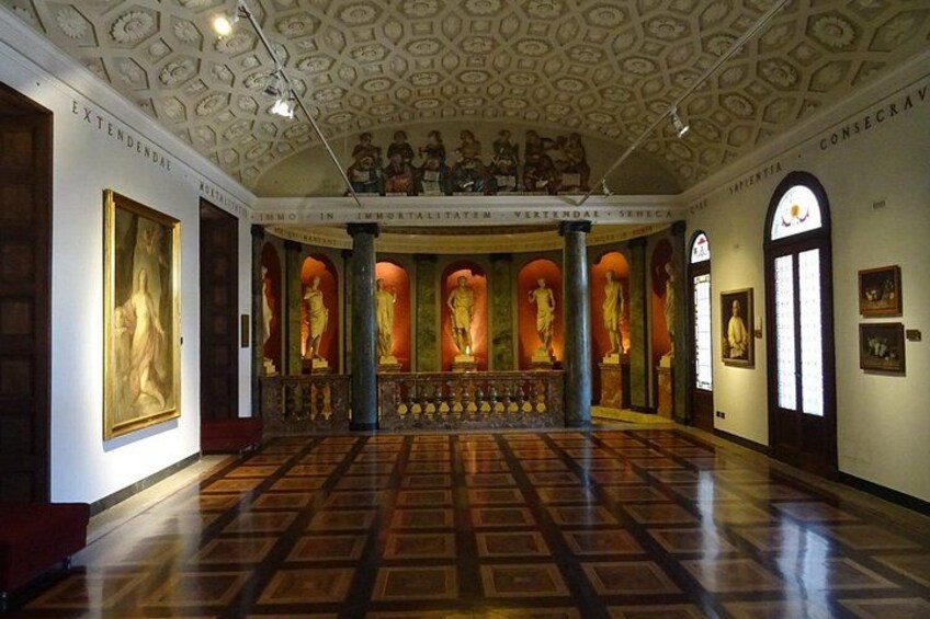 A grand hall with a patterned floor, statues, and a ceiling with intricate designs. 2