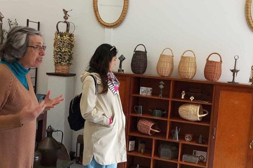 Two people in a room with a wooden cabinet displaying various baskets and kitchen items. 3