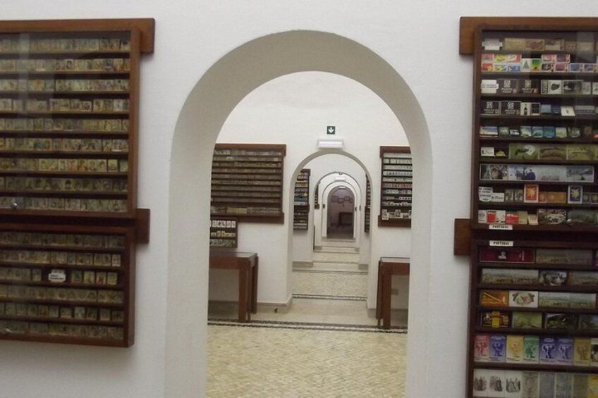 An indoor corridor with arched doorways, leading to a central staircase. 4