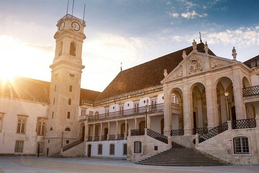Un edificio histórico con una torre de reloj, balcones arqueados y una escalera que conduce a la entrada. 2