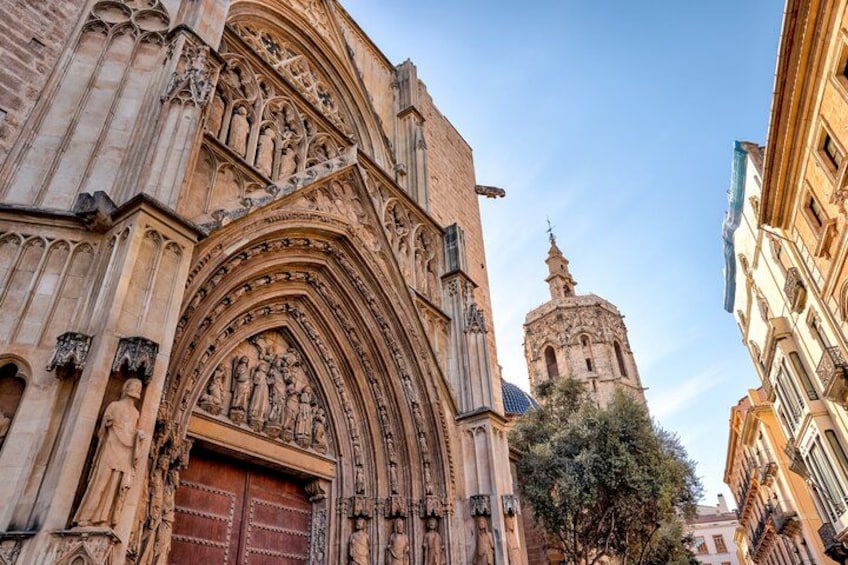 A Gothic cathedral with intricate stone carvings and a large wooden door. 1