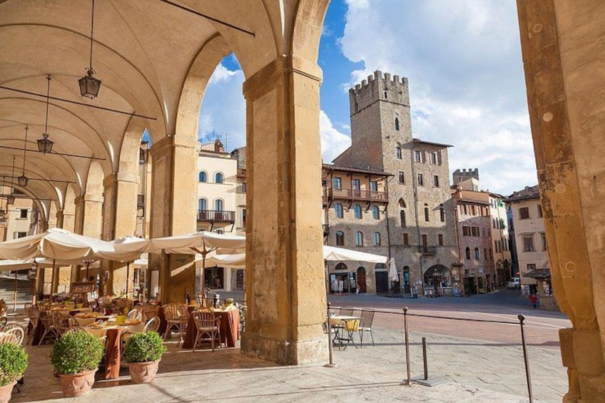 Un café en plein air avec des arcades, des tables, des chaises et des plantes en pot. 1