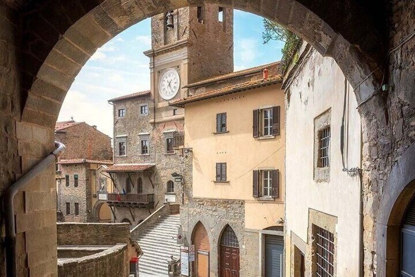 An old town with stone buildings, a clock tower, and an archway. 3