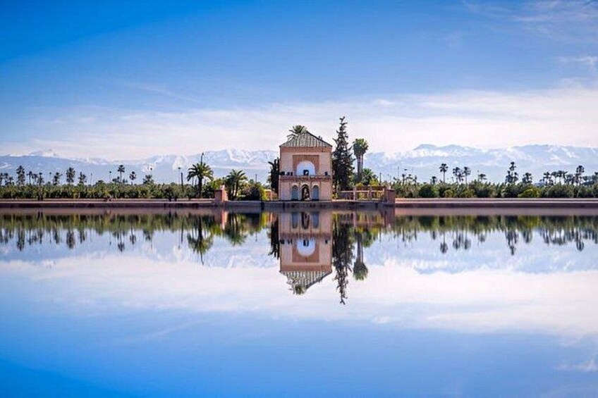 Un bâtiment dont le reflet se mire dans une étendue d’eau calme, entouré de palmiers et avec des montagnes en arrière-plan. 3