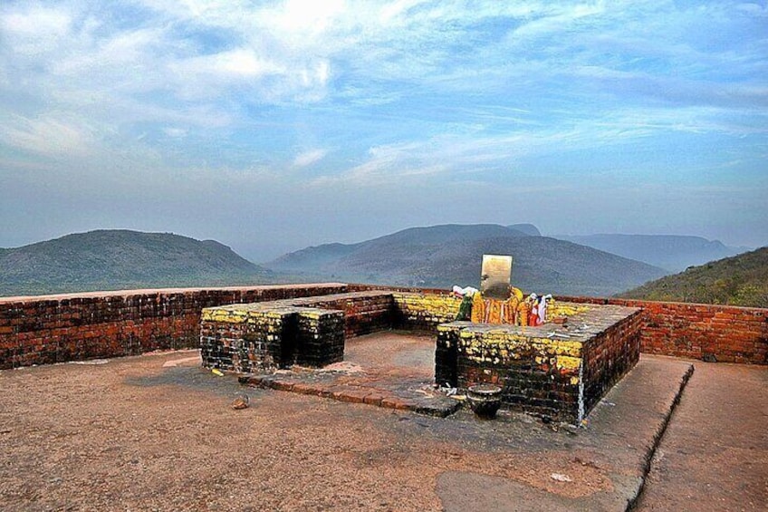 Eine historische Festung mit Ziegelmauern und einem gepflasterten Bereich, die auf eine hügelige Landschaft blickt. 1