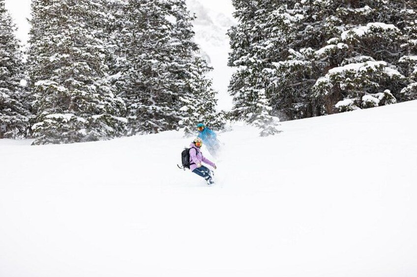 A person snowboarding down a snowy slope with trees in the background. 5