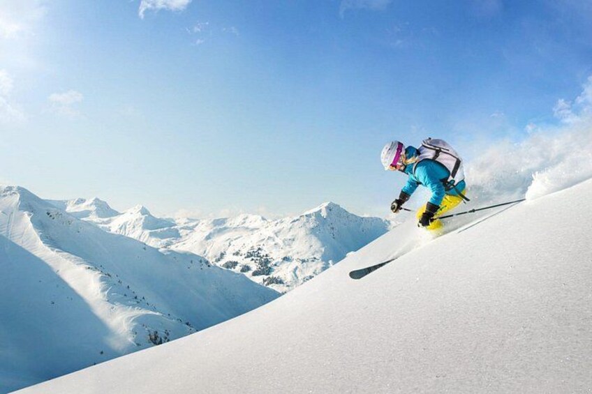 A skier in blue and yellow gear on a snowy mountain slope. 4