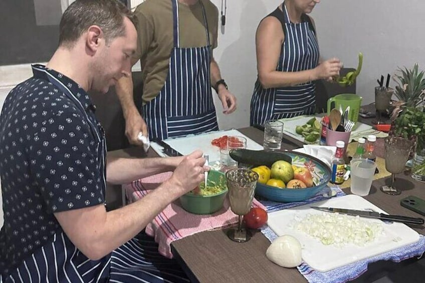 A group of people preparing food, with vegetables and a bowl of salad on the table. 2