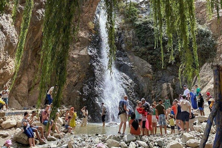 A waterfall in a rocky area with people gathered around. 4